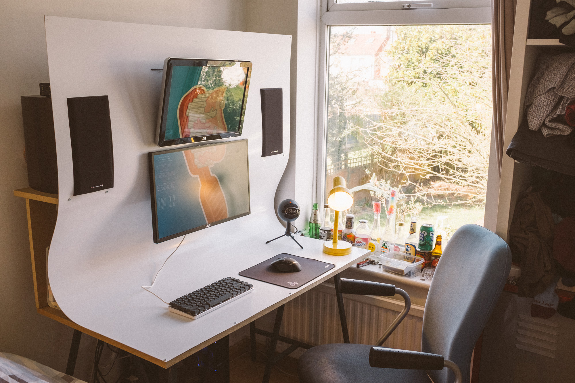 Picture of a desk with MDF frame, white plastic surface that curves up to contain integrated monitors and speakers