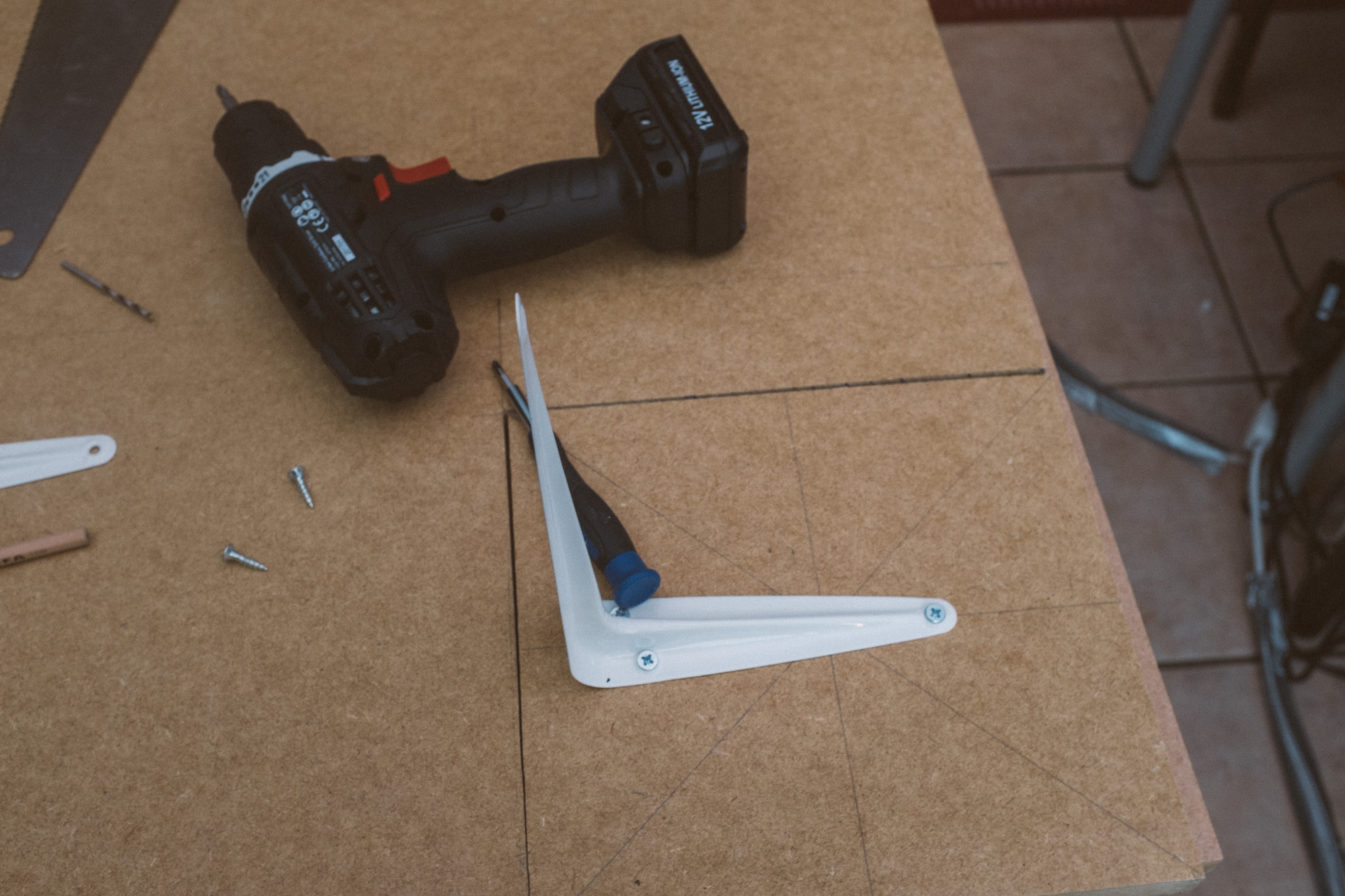a drill sat on the MDF alongside a cut out speaker shelf attached to a shelving bracket